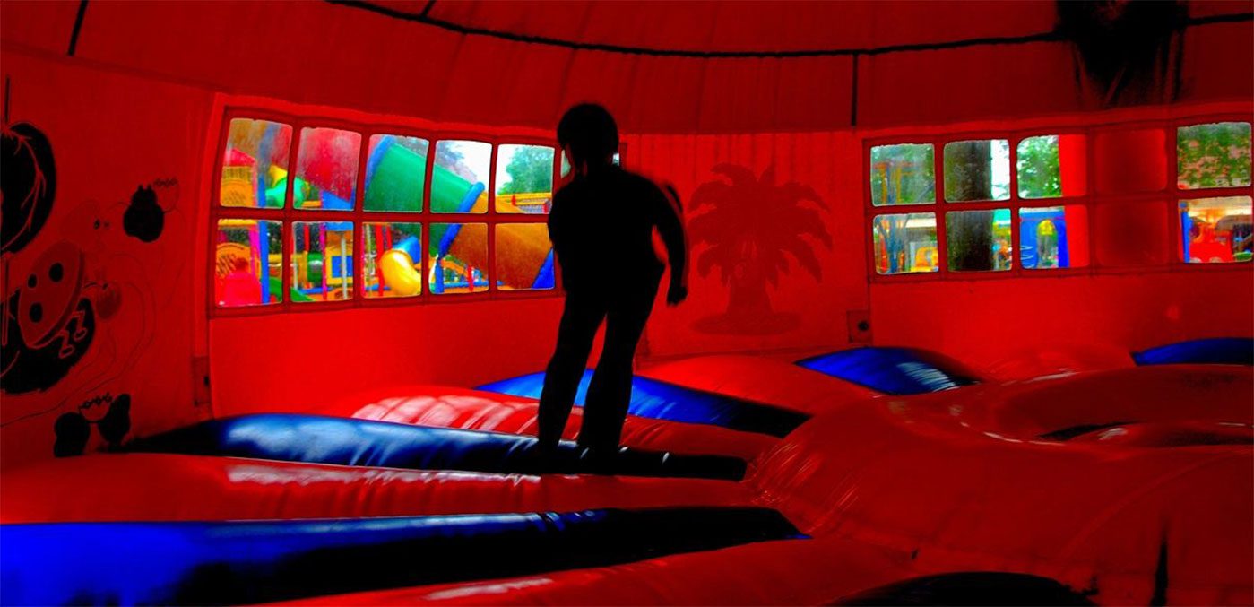 A person riding on the ground in an indoor trampoline park.