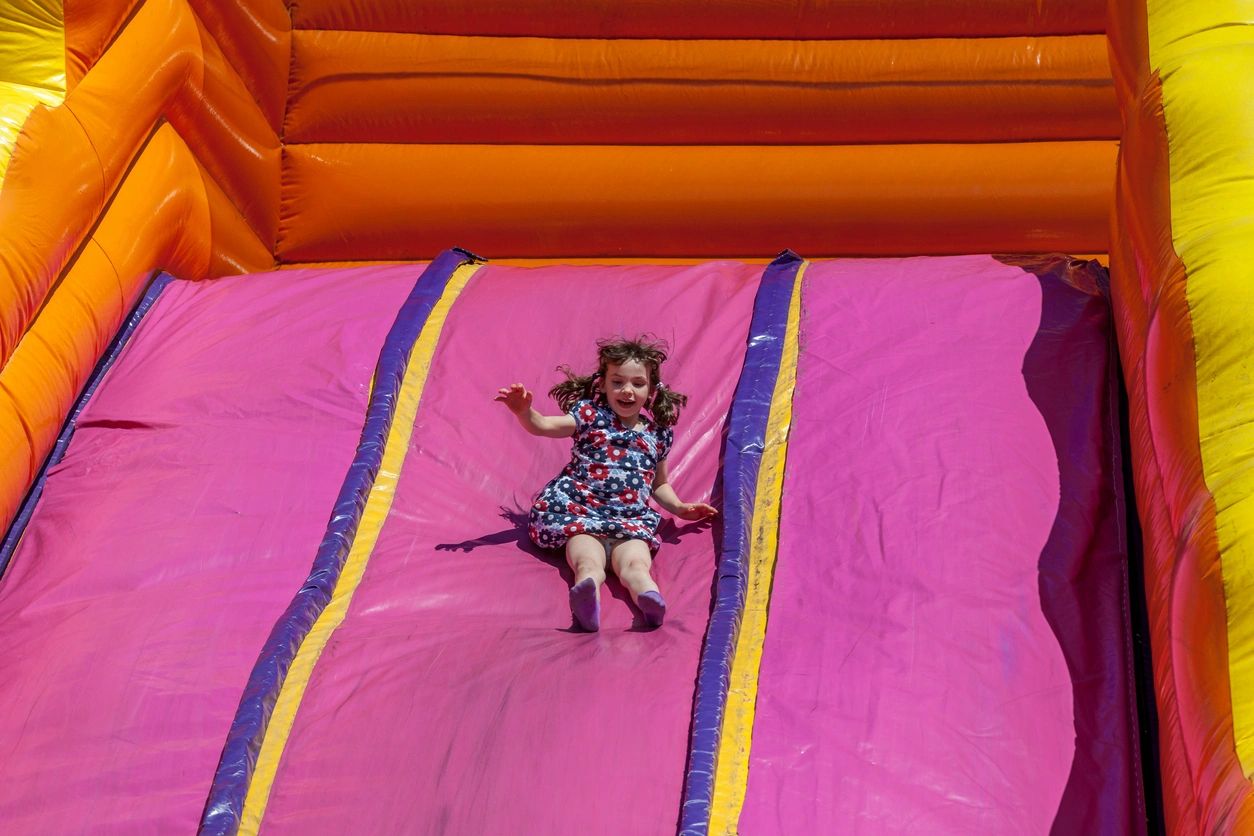A little girl is on the slide at an amusement park.