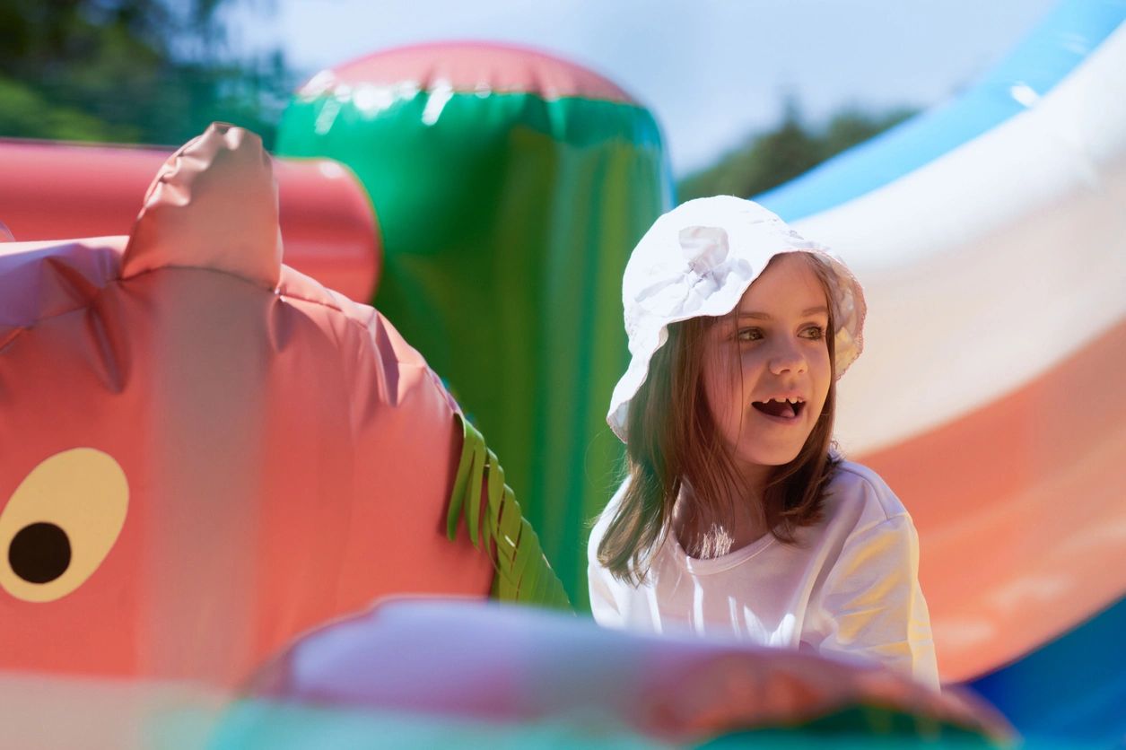 A girl in white shirt and hat on inflatable slide.